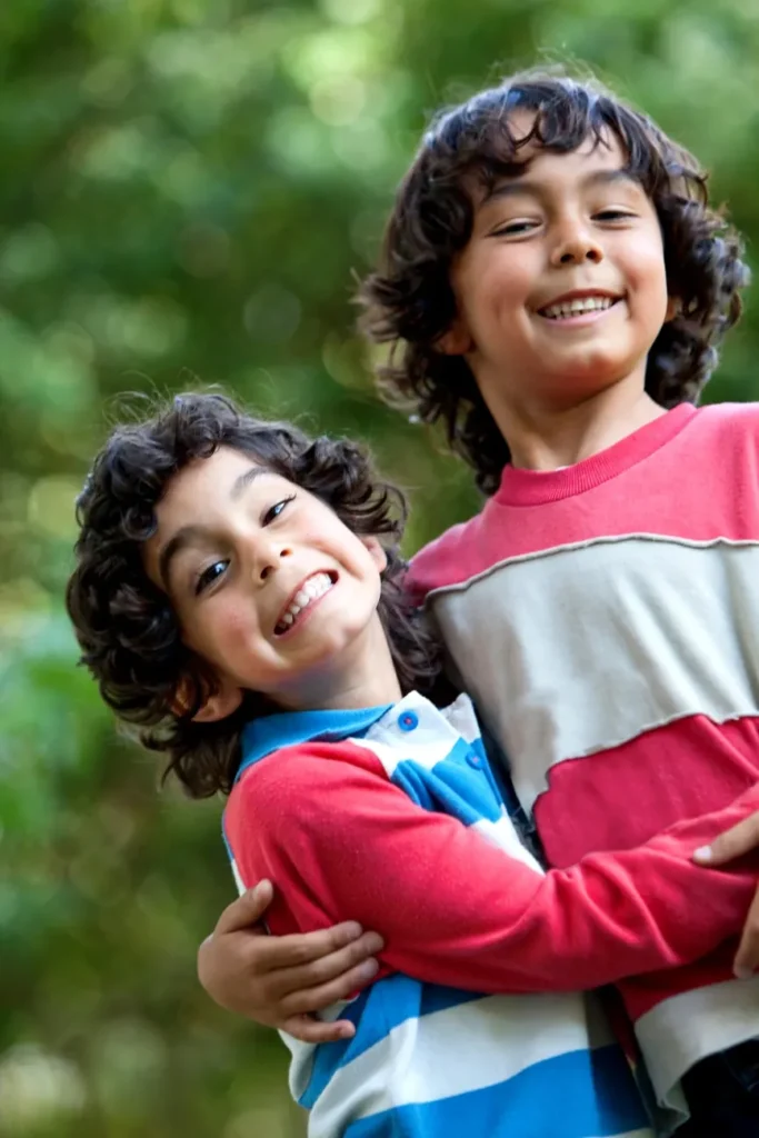 Dos niños sonriendo y abrazados al aire libre