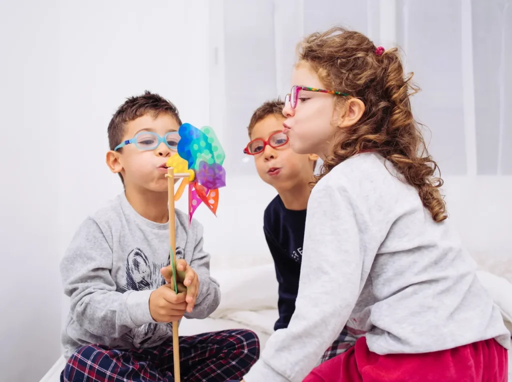 Tres niños soplando un molinillo de colores