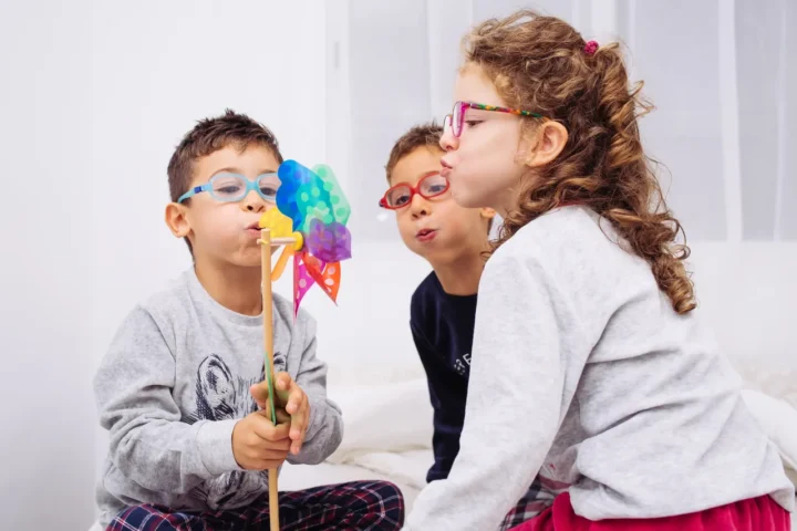 Tres niños soplando un molinillo de colores